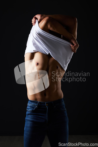 Image of Fitness, undressing and muscle with man in studio for strong, body and health. Sports, wellness and workout with person and remove tshirt on dark background for fashion, gym and athlete motivation