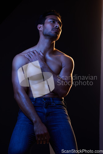 Image of Sexy, muscle and man with fitness, wellness and posing on a dark studio background. Person, guy and model with jeans, shirtless and atmosphere with training, power and body goals with aesthetic