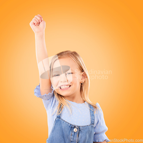 Image of Hand up, portrait and girl child in studio happy, excited and celebrating success on orange background space. Face, smile and kid winner with victory fist for good news, promotion or prize giveaway