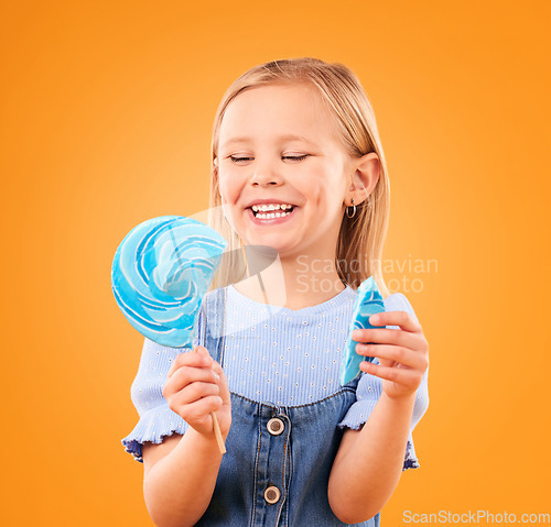 Image of Lollipop, candy and a child laughing in studio for sweet tooth, color spiral or sugar for energy. Face of happy girl kid on orange background for funny snack or thinking of dessert or unhealthy food