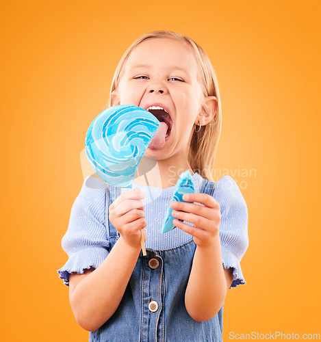 Image of Lollipop, candy and portrait of a child in studio for sweets, color spiral or sugar for energy. Face of happy girl kid excited on orange background to lick or eating snack, dessert or unhealthy food