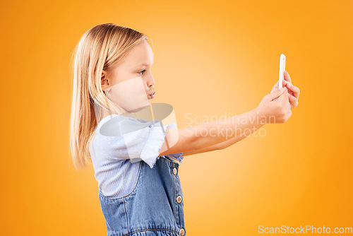 Image of Phone, selfie or profile of kid in studio with confidence or mockup space in photograph memory. Pout, orange background or young girl child taking picture online on a social media app on internet