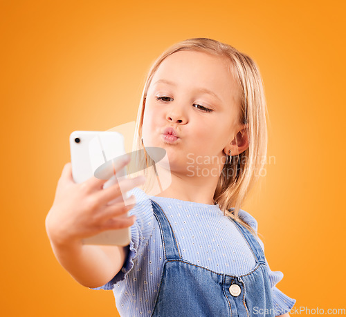 Image of Kiss, selfie or face of kid in studio with confidence or mockup space in photograph memory. Web, orange background or young girl taking fun pictures online on a social media app to post on internet