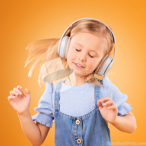 Image of Headphones, dancing or child streaming music to relax with freedom in studio on orange background. Hair, moving or girl dancer listening to a radio song, sound or gospel on an online subscription