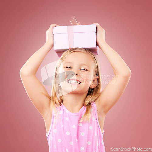 Image of Gift, present and child with box on head for birthday, holiday or happy celebration. Portrait of excited girl on a pink background for surprise, giveaway prize or celebrate kindness for charity