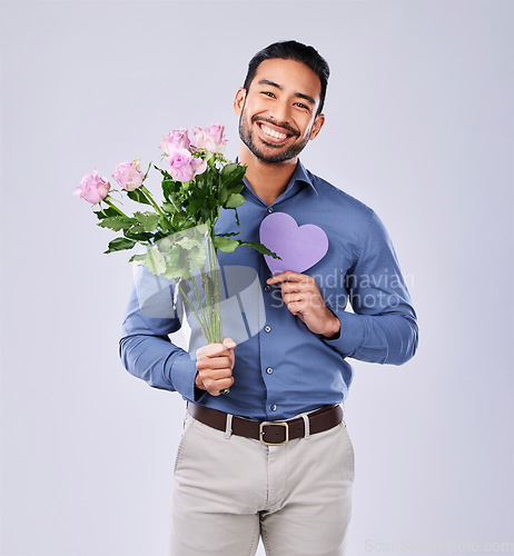 Image of Purple heart, portrait and asian man with roses in studio for thank you, gift or care on grey background. Paper, frame and Japanese male model with flower, bouquet or offer, love or valentines day