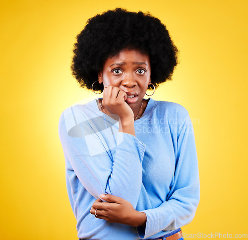 Image of Biting nails, anxiety and a scared woman in studio for fear, mental health or nervous behaviour. Portrait of African person on yellow background worried, stress or panic for phobia, terror or horror