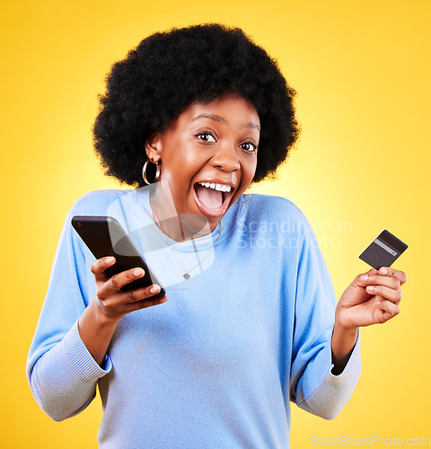 Image of Happy black woman, portrait and phone with credit card in online shopping against a yellow studio background. Excited African female person with afro on smartphone for ecommerce, payment or banking