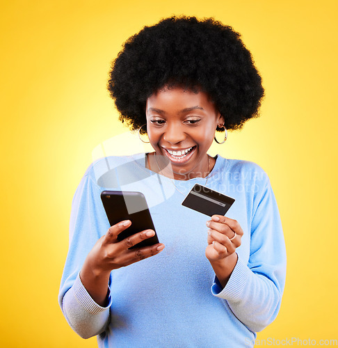 Image of Happy black woman, phone and credit card in online shopping against a yellow studio background. Excited African female person with afro smile on mobile smartphone app in ecommerce, payment or banking