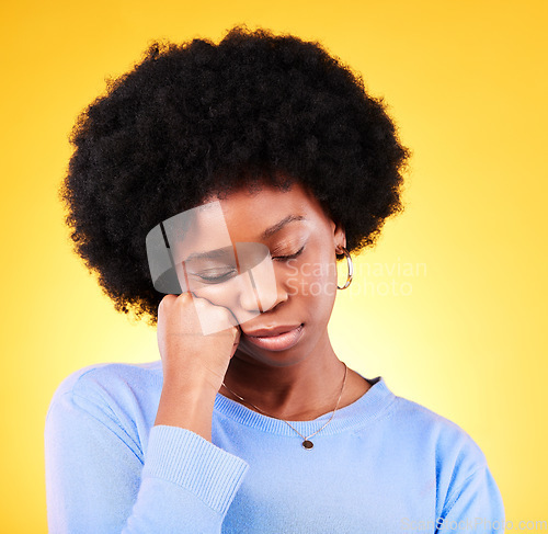 Image of Tired, black woman and hand on face in studio looking sad, fatigue and burnout of depression and mental health. Exhausted, person and stress with crisis, anxiety and problem on yellow background