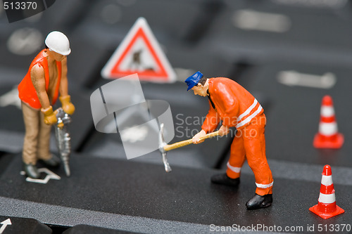 Image of Miniature figures working on a computer keyboard.