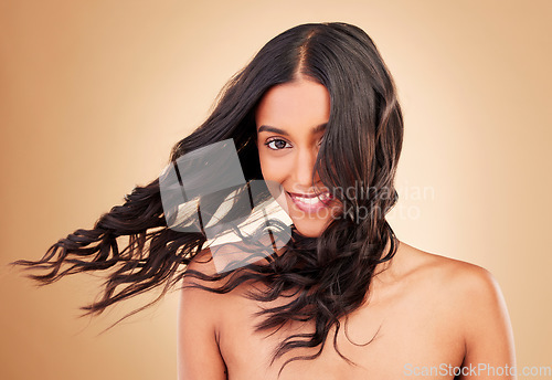 Image of Portrait, woman and curly hair in wind on studio background for shine, beauty and keratin shampoo. Happy indian model, hairstyle and waves in breeze for aesthetic texture, growth and salon cosmetics