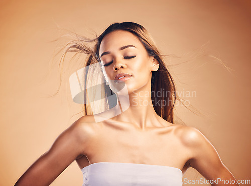 Image of Beauty, hair and wind with a natural model in studio on a brown background for keratin treatment. Skin, shampoo and body with a confident young woman at the salon for growth or aesthetic haircare