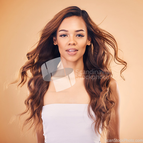 Image of Portrait, woman and curly hair for beauty in studio isolated on a brown background. Long face, wavy hairstyle and natural cosmetics of model in salon treatment for health, wellness or hairdresser