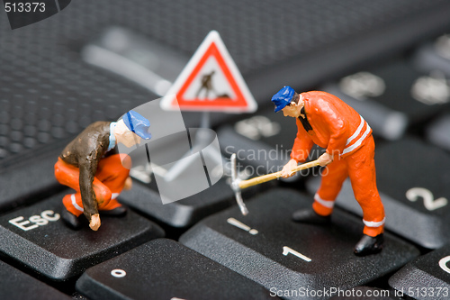 Image of Miniature figures working on a computer keyboard.