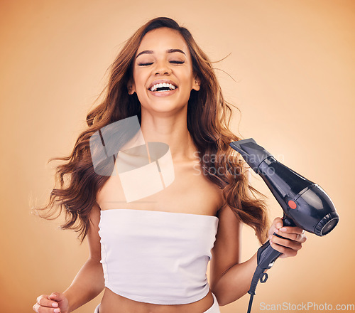 Image of Hair dryer, happy and a woman in studio for beauty, cosmetics and shine. Aesthetic model person laugh on brown background for heat treatment, healthy results and hairdresser or salon blow out product
