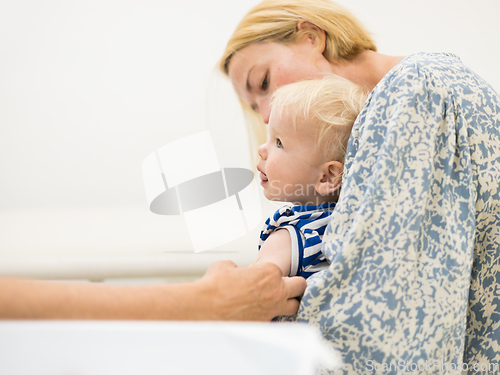 Image of Child beeing vaccinated by pediatrician in presence of his mother. Preventive vaccination against Diphtheria, whooping cough, tetanus, hepatitis, haemophilus influenzae, pneumococcus, poliomyelitis