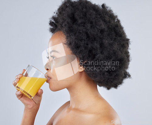 Image of Woman, glass and orange juice in studio for beauty of vitamin c benefits on gray background. Face, african model and drink citrus fruit smoothie for healthy skin, weight loss diet and detox nutrition