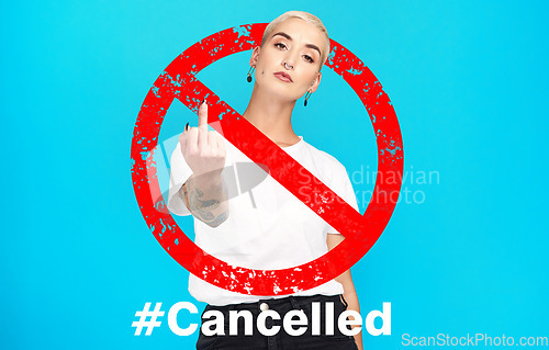 Image of Portrait, rude and cancel culture with a woman on a blue background in studio to reject or deny an icon. Social media, hashtag and censorship with a rebel girl showing a hand gesture in protest