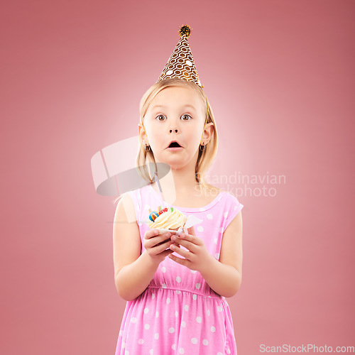 Image of Portrait, surprise and kid with cupcake at birthday in studio isolated on a pink background mockup space. Face, wow of child and cake at party in hat at celebration, food event and shocked at dessert