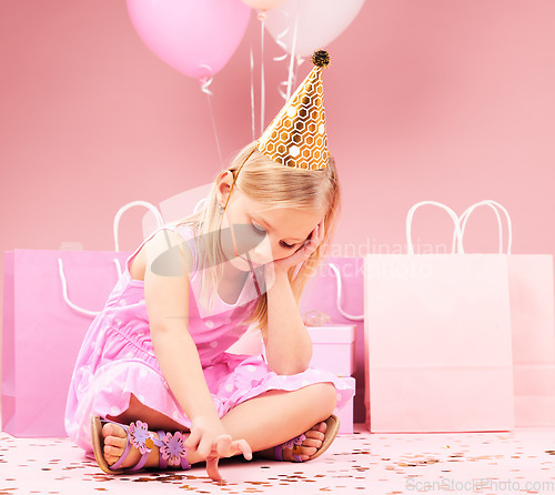 Image of Depression, sad birthday and child on pink background disappointed for party, celebration and event. Lonely, emotion and unhappy, lonely and upset girl with balloons, presents and gifts in studio