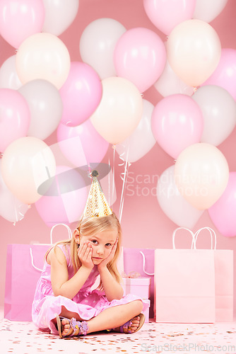 Image of Depression, sad birthday and portrait of girl on pink background for party, celebration and event in studio. Upset, emotion and unhappy, lonely and disappointed child with balloons, presents or gifts