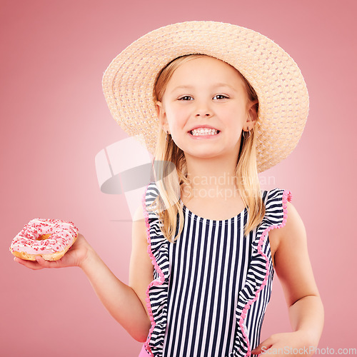 Image of Happy, portrait and girl with a donut or child with sugar, dessert and sweet craving on pink background in studio. Face, smile and hungry kid with donuts on holiday, vacation or weekend diet