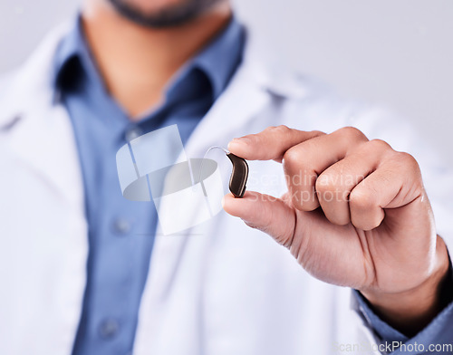 Image of Closeup, hand and a hearing aid from a doctor for communication, medical support or service. Healthcare, sound and a person or surgeon with an ear piece for listening, audiology or helping with gear