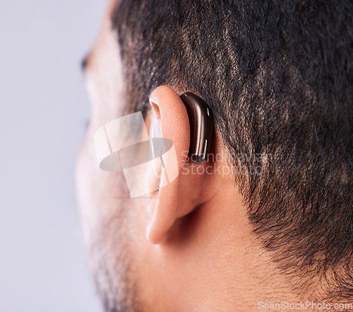 Image of Ear, deaf and hearing aid closeup in studio on a gray background for sound, audio or communication. Technology, listening and a man with a disability closeup for implant or medical innovation