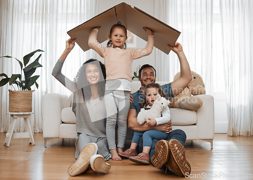 Image of Parents, children and cardboard roof in portrait, smile or excited for security, real estate or fresh start in family home. Mother, dad and kids on floor, box and happy together for support in house