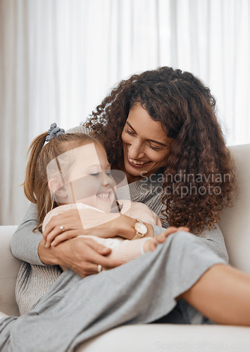 Image of Love, hug and mother with girl child on a sofa happy, playing and bonding in their home together. Family, smile and kid with mom in a living room embrace, relax and enjoy weekend, day off or break