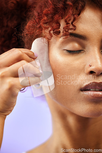 Image of Skincare, face and woman with gua sha in studio for facelift, wellness or anti aging on purple background. Beauty, crystal and lady model relax with facial, massage or lymphatic drainage for collagen