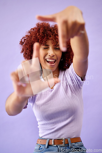 Image of Portrait, hands frame and happy woman wink in studio isolated on a purple background. Face, finger border and person excited for photographer selfie, profile picture and smile in creative perspective