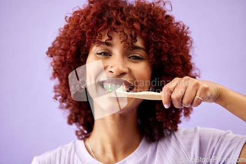 Image of Face, smile and woman brushing teeth with bamboo in studio isolated on purple background. Portrait, wood toothbrush and happy person cleaning for eco friendly hygiene, dental health or sustainability