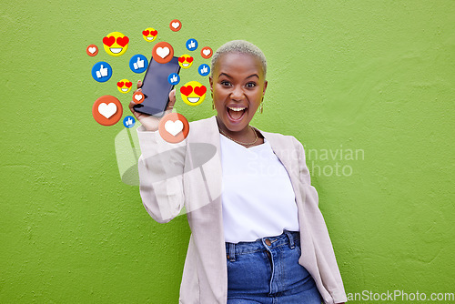 Image of Portrait, excited black woman and phone emojis, social media icons and thumbs up notification. Smartphone communication, like opinion vote and African user show feedback on green background wall