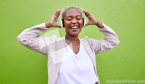 Image of Music, headphones and happy black woman dance on green wall background mockup space. Radio, singing and African person streaming podcast, hearing audio or listening to sound of jazz media for freedom