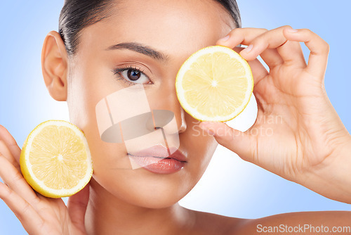 Image of Lemon, portrait and beauty of woman in studio for vitamin c cosmetics, natural diet and detox. Face of model, healthy skincare and citrus fruits on eyes for sustainable dermatology on blue background