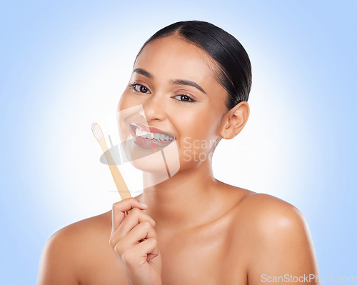 Image of Happy portrait, woman and brushing teeth in studio for dental care, gingivitis and sustainable cosmetics on blue background. Model with bamboo toothbrush cleaning mouth, oral hygiene or healthy smile