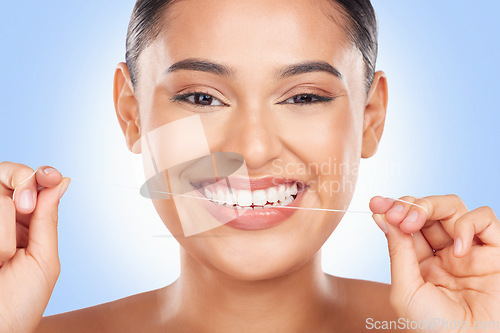 Image of Woman, portrait and floss teeth in studio for healthy dental care, gingivitis and plaque on blue background. Face, happy model and oral thread for cleaning mouth, tooth or fresh breath of gum hygiene