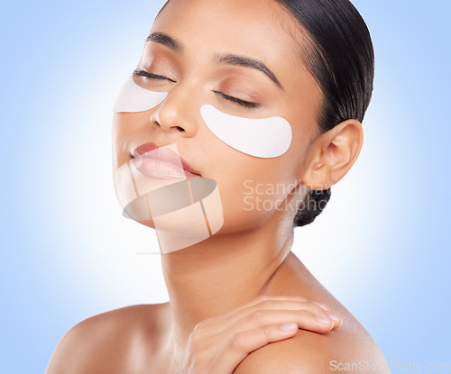 Image of Skincare, beauty and woman with eye pads for anti aging or skin glow on blue background. Cosmetics, facial detox and face of model with luxury mask or collagen product for dermatology pads in studio.