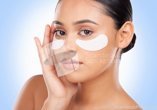 Image of Portrait, skincare and eye mask with a natural woman in studio on a blue background for antiaging treatment. Face, beauty and wellness product with a young model at the salon for a facial application