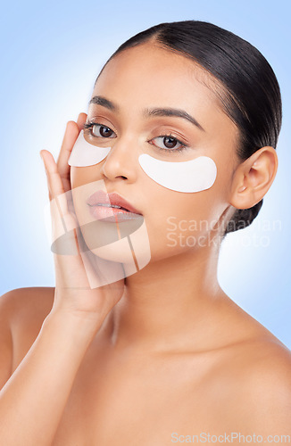 Image of Eye patch, skincare and woman with portrait and face health, dermatology and self care shine in studio on blue background. Beauty, person and facial product with collagen mask, wellness and glow