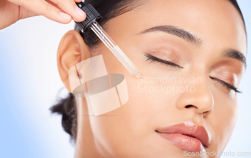 Image of Essential oil, facial and woman in studio for skincare, wellness or hydration serum application on blue background. Hyaluronic acid, vitamin c or retinol for lady face, collagen or cosmetic treatment