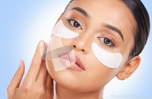 Image of Portrait, beauty and eye mask with a natural woman in studio on a blue background for antiaging treatment. Face, skincare and wellness product with a young model at the salon for a facial application