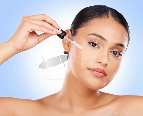 Image of Skincare, portrait and woman in studio with oil for beauty, wellness or serum application on blue background. Hyaluronic acid, vitamin c or retinol facial for female face, mask or cosmetic treatment
