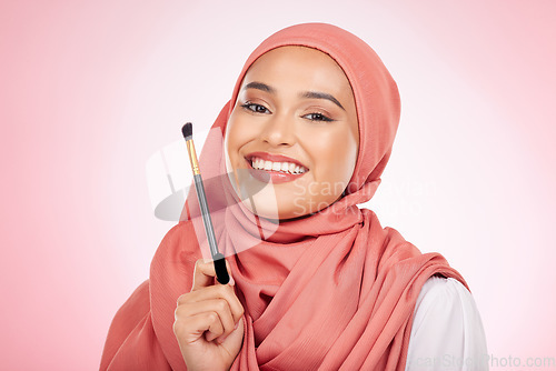 Image of Portrait, beauty and muslim woman with makeup brush in studio for wellness and cosmetics on pink background. Halal skincare, face and female with hijab for luxury, glamour or Islamic safe products