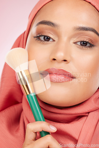 Image of Cosmetics, brush and portrait of Islamic woman with makeup artist tools, beauty product and self care glow. Facial powder application, studio and hijab face of Arabic Muslim model on pink background