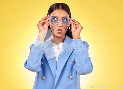 Image of Funny, happy woman and sunglasses with kiss, comedy and silly face in a studio. Yellow background, pout and young female person with modern fashion, trendy cool style and creative work clothing