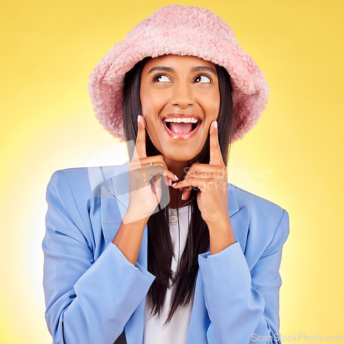 Image of Fashion, thinking and face of woman on yellow background with funny, goofy and playful expression. Emoji, happiness and happy person in studio smile h in trendy clothes, style and outfit with hat