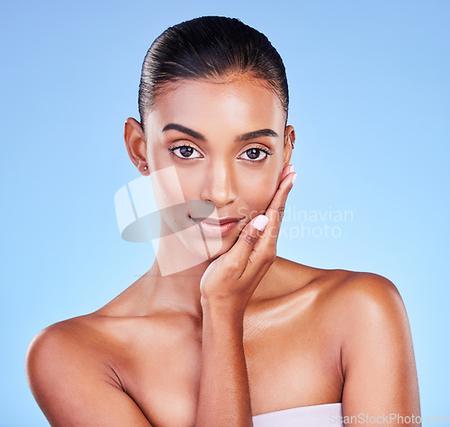 Image of Skincare, woman and hand on face in studio for wellness, cosmetic or treatment on blue background. Portrait, beauty and lady model touching glow, skin or smooth, dermatology or results satisfaction